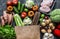 Grocery paper bag with fresh organic vegetables, fruits, meat on a dark background, top view. Healthy diet food concept