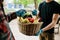 A grocery store delivery man wearing a black polo-shirt delivering food to an old man at home