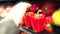 Grocery store lose up hand stocking peppers on a shelf wearing gloves