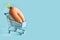 Grocery trolley with ugly carrot on blue. Space for text