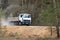 GRODNO, BELARUS - APRIL 2020: Heavy laden multi-ton truck MAZ with white cab and gray body rides along dusty country road in with