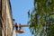 Grodno, Belarus, October 11, 2018: Two builders repairing the roof of a old brick building. People on the crane platform. Crane on