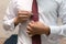 The groom adjusts the clip on the burgundy tie