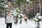 Groom in beige pullover on background of blurred bride in snowy forest. Winter wedding. Artwork.