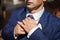 Groom in a blue suit adjusts his tie