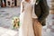 Groom and bride with a bouquet are standing on a sunny street. Cropped. Faceless