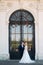 Groom and bride neat the big door of great palace