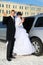 Groom and bride stand near wedding limousine