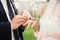 Groom and bride during wedding ceremony, close up on hands exchanging rings. Wedding couple and outdoor wedding ceremony