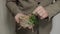 Groom in brown jacket holding wedding rings on wooden stand on the palm of hand. Man touches rings