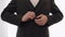 Groom buttoning jacket, man in suit fastens buttons on his jacket preparing to go out