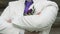 The groom dressed in a white suit with purple tie