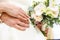 Groom embraces the bride with wedding white rose bouquet. rings on the hands of newly-married couple