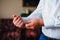 Groom fastens cufflinks on the sleeve of a white shirt.