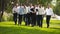 Groom flexing and having fun walking with groomsmen on wedding day. Happy classy man in black suit, bow tie and