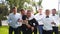 Groom flexing and having fun walking with groomsmen on wedding day. Happy classy man in black suit, bow tie and