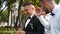 Groom flexing and having fun walking with groomsmen on wedding day. Happy classy man in black suit, bow tie and