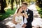 Groom with glasses and bride with a bouquet of peonies gently hug in the park