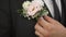 Groom with hand adjusts boutonniere made of fresh eustoma flowers