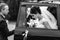 Groom helps bride to step out of the black car