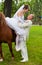 groom helps fiancee to get down from a horse