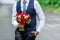 Groom holding in hands delicate, expensive, trendy bridal wedding bouquet of flowers in marsala and red colorsry attached to the b