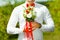 Groom holding in hands delicate, expensive, trendy bridal wedding bouquet of flowers in red and white