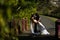 Groom holding wife and kissing on a bridge