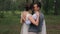 Groom holds bride on arms on photoshoot in forest outdoors