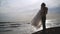Groom holds bride in his arms on background of sea. Action. Groom picked up bride and turns her in sun on background of