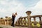 Groom holds bride& x27;s hand while she sits on ol stone handrails