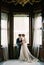 Groom holds the hands of bride standing at the window of the old villa. Como, Italy