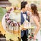 Groom holds tasty wedding cake while bride reaches for a kiss