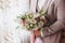 The groom holds a wedding bouquet in his hands