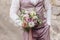 The groom holds a wedding bouquet in his hands