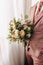 The groom holds a wedding bouquet in his hands