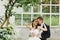 Groom hugs a bride from behind standing under the trees