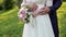 The groom hugs the bride, the bride holds a bouquet, the camera moves at the level of the belt