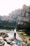 Groom hugs bride while standing on the stones. Back view