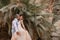 Groom hugs and kisses of bride on background of palm trees and rocks.