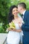 Groom kiss happy bride with bouquet. Woman and man smile on wedding day. Wedding couple in love. Newlywed couple on