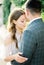 Groom kisses the bride on the forehead, hugging her waist. Portrait