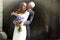 Groom kisses bride\'s cheek hugging her from behind in the rays o