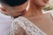 The groom kisses the bride on the shoulder. Sensual portrait of young elegant just married pair