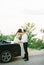 Groom kisses bride sitting on the bumper of a sports convertible