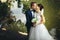 Groom kisses a bride standing on the lake shore