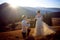 Groom kisses hand of bride. Sunset in the mountains on background.