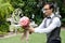 The groom kneel down and holding a bouquet for propose marriage to girl friend in the garden.