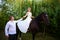 The groom leads the horse by the bridle. Bride sits in the saddl