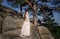 Groom looks at beautiful bride standing on the rocks